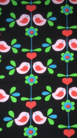 svart tyg med små fåglar, hjärtan och blommor.